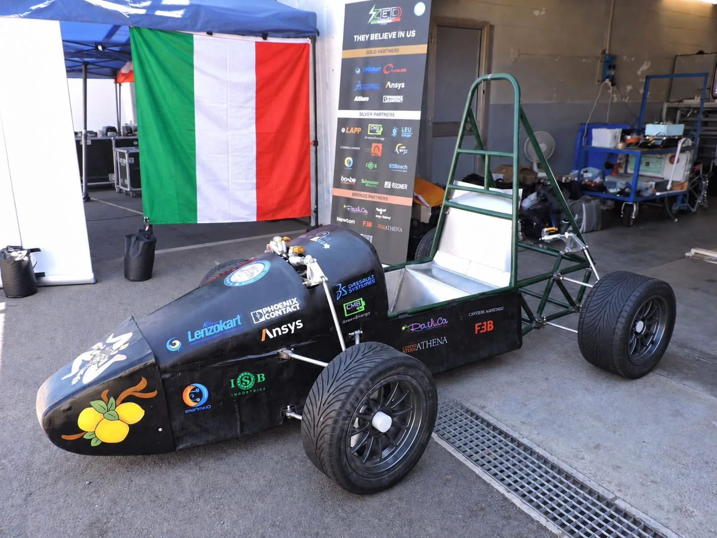 La monoposto Zancle E-Drive nel box, accanto alla bandiera italiana